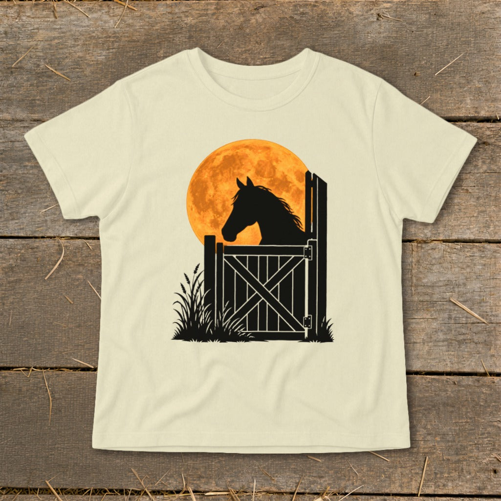 Cream-colored short-sleeve t-shirt featuring a black silhouette of a horse looking out a stable gate against an orange full moon.