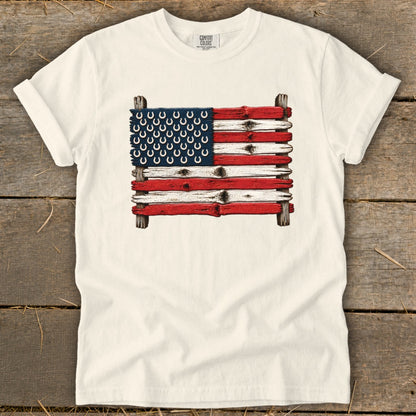 A cream t-shirt features a graphic of the American flag made of painted wooden planks and horseshoes.