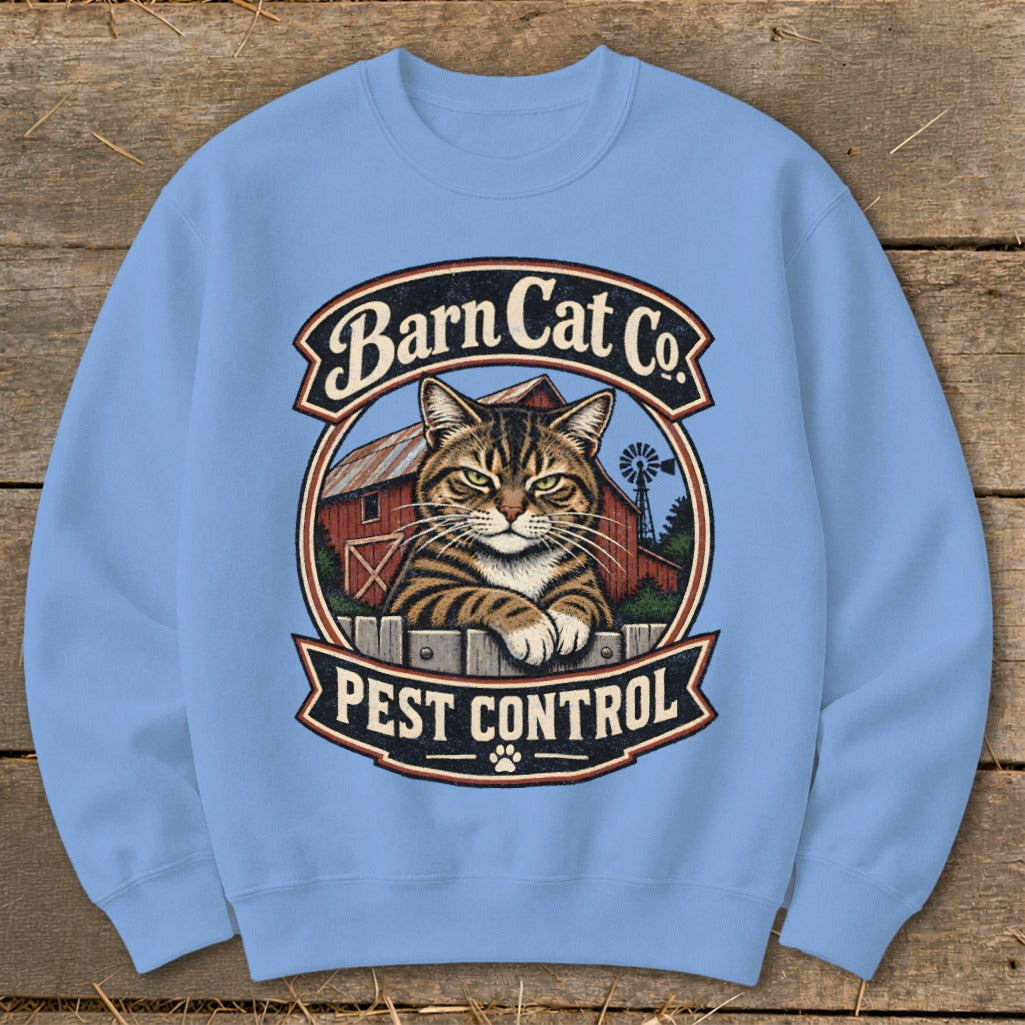 Light blue crewneck sweatshirt featuring a graphic of a tabby cat behind a fence with a barn background and text reading Barn Cat Co. Pest Control.