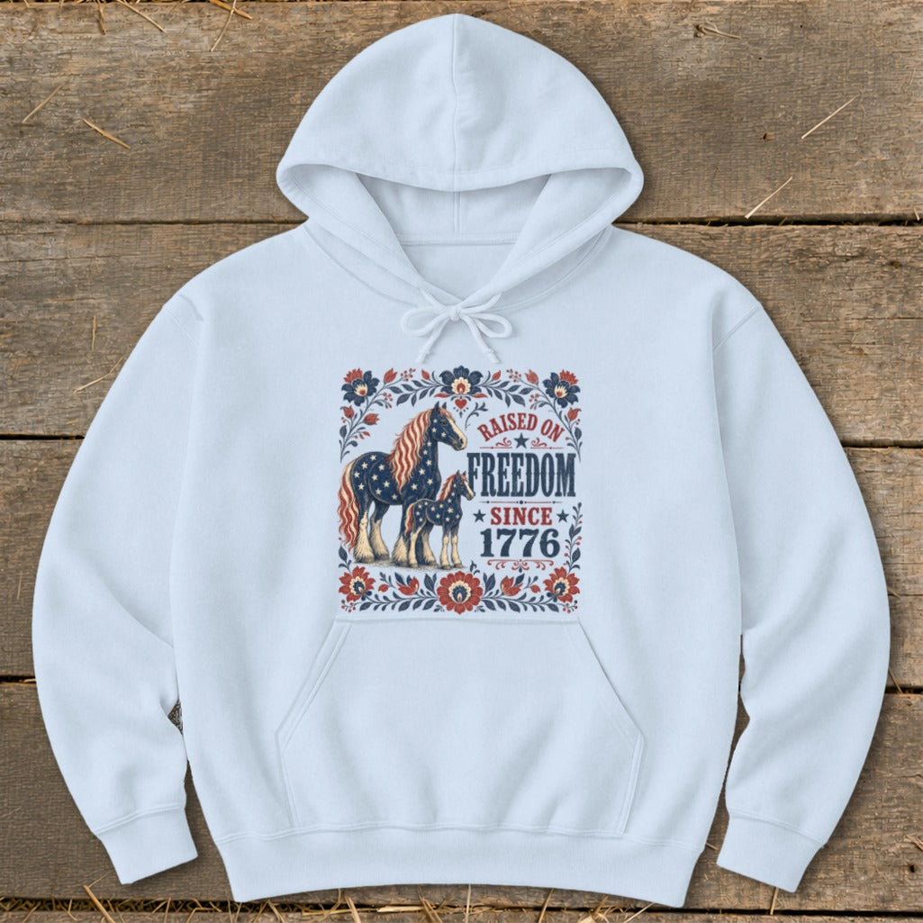 White hoodie with graphic of two horses and text "Raised on Freedom Since 1776".