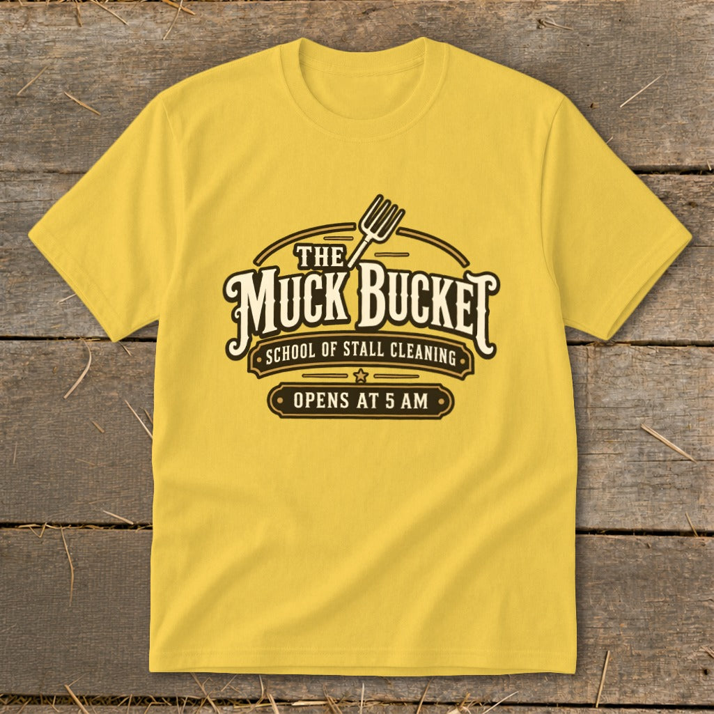 Yellow t-shirt with "The Muck Bucket School of Stall Cleaning Opens At 5 AM" logo.