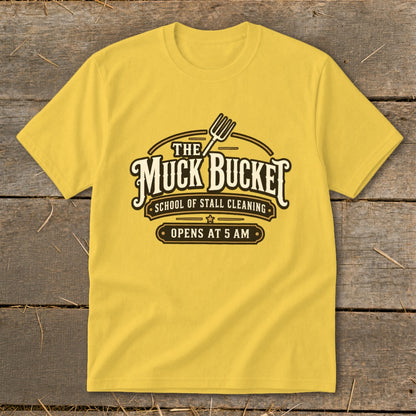 Yellow t-shirt with "The Muck Bucket School of Stall Cleaning Opens At 5 AM" logo.