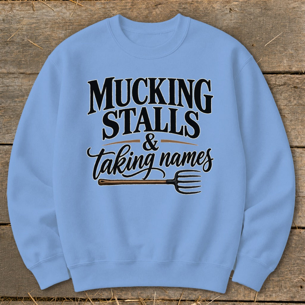 Light blue sweatshirt with "Mucking Stalls & Taking Names" text and pitchfork graphic.