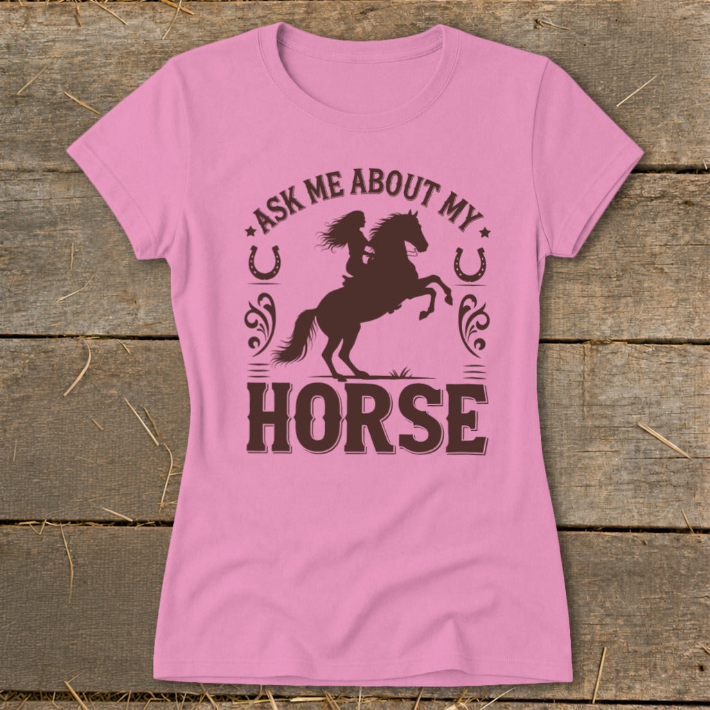 Pink t-shirt with brown graphic of a woman riding a rearing horse and text "Ask Me About My Horse."