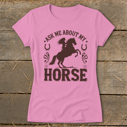 Pink t-shirt with brown graphic of a woman riding a rearing horse and text "Ask Me About My Horse."