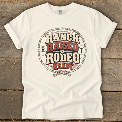 A white t-shirt featuring a circular graphic with the text Ranch Raised Rodeo Ready.