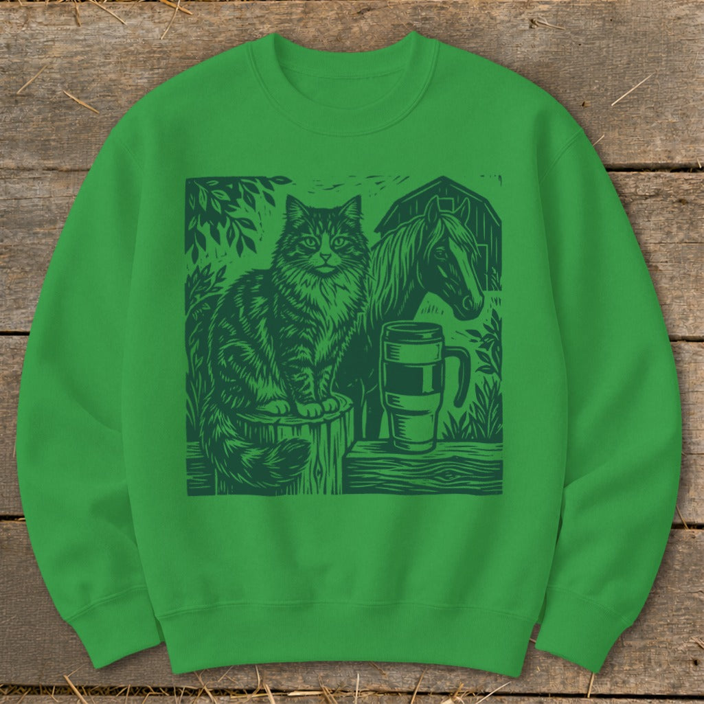 Green sweatshirt with a dark green linocut design of a cat, horse, and mug.