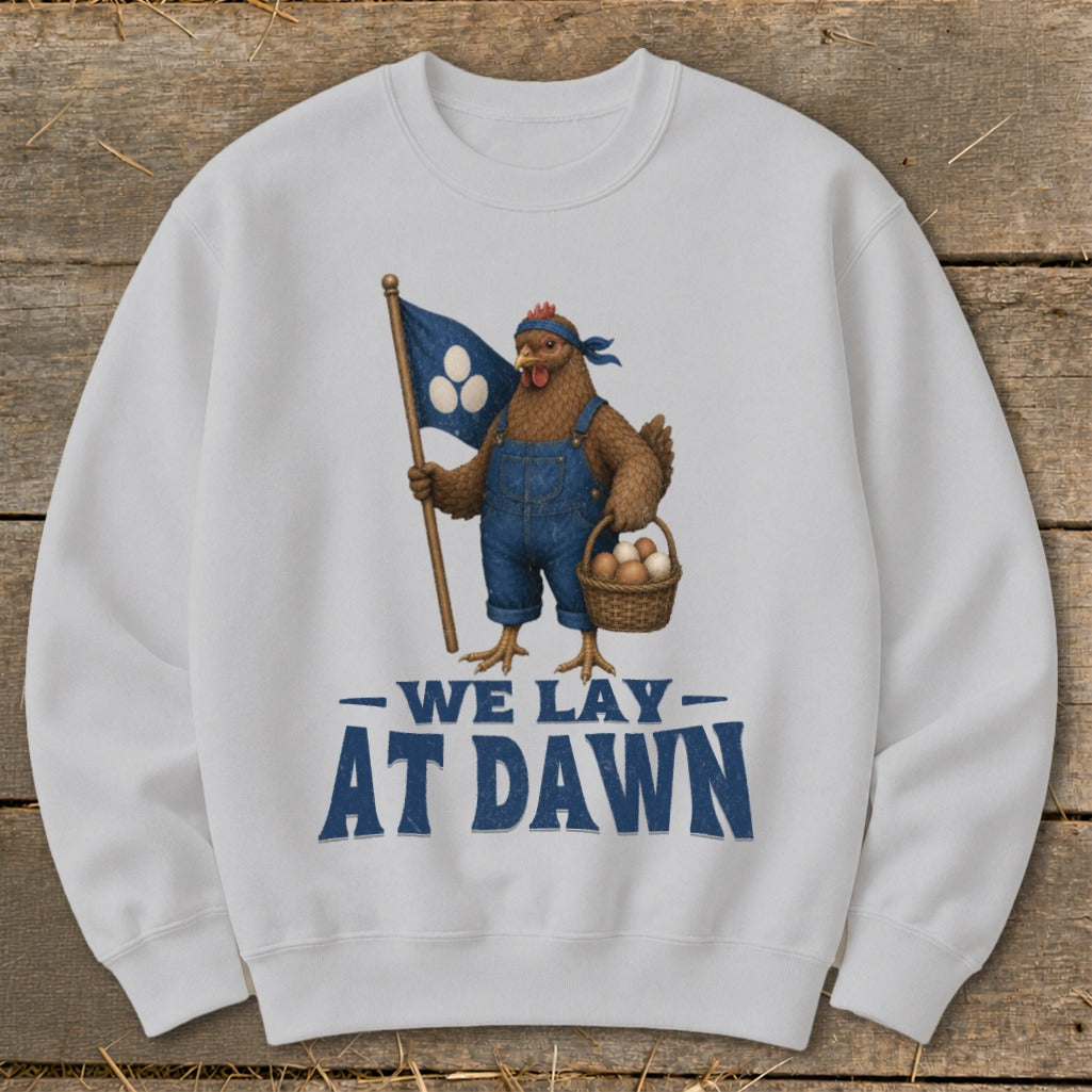 Chicken in overalls holds a flag and basket of eggs; text says "We Lay At Dawn".