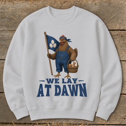 Chicken in overalls holds a flag and basket of eggs; text says "We Lay At Dawn".