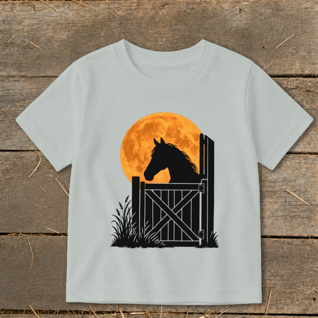 Light gray children's t-shirt featuring a black silhouette of a horse looking out from a barn door against a large orange moon.