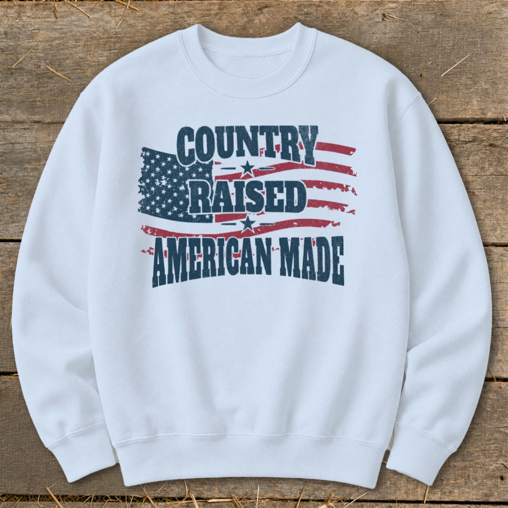 White sweatshirt with "Country Raised American Made" text and distressed US flag graphic.