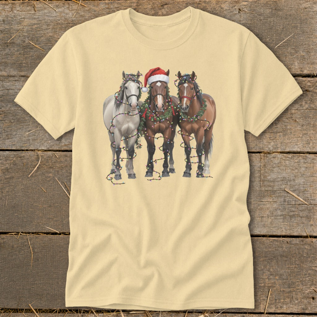 Three horses wearing Christmas decorations and lights on a cream t-shirt.