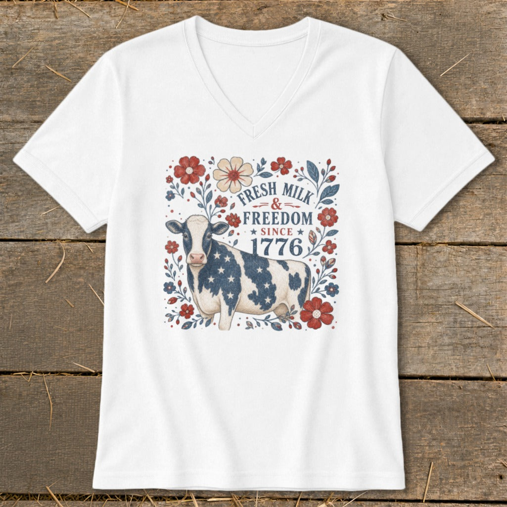 White v-neck shirt with a cow in stars and stripes, surrounded by flowers and text.