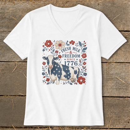 White v-neck shirt with a cow in stars and stripes, surrounded by flowers and text.