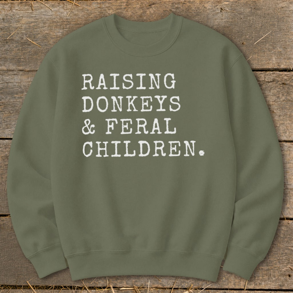 Olive green sweatshirt with white text: "Raising Donkeys & Feral Children."