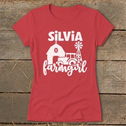 Red t-shirt with white graphic of a barn, tractor, windmill, and text "SILVIA farmingirl".