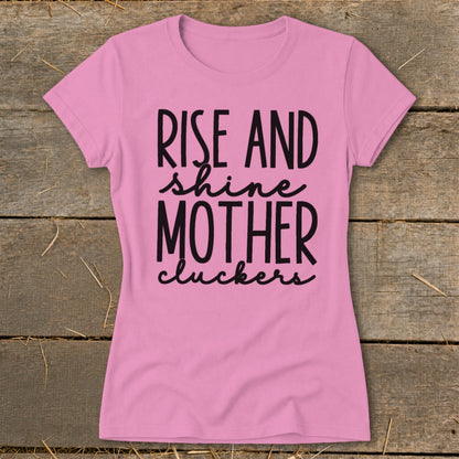 Pink t-shirt with black text that reads "RISE AND shine MOTHER cluckers."