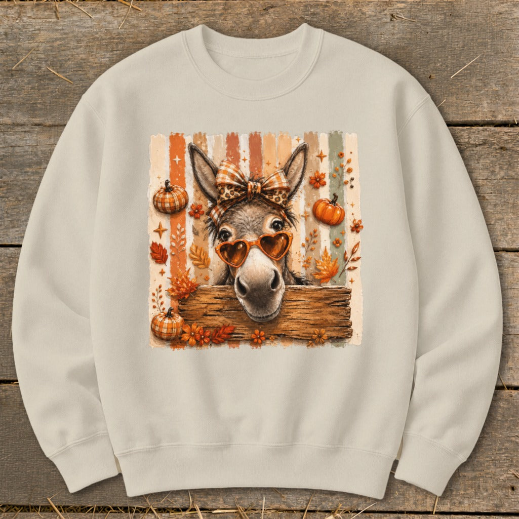 Cute donkey with heart sunglasses and bow on striped background with pumpkins and leaves.