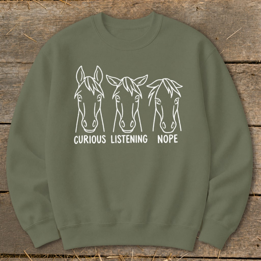An olive green crewneck sweatshirt with a white horse ear position graphic and text that reads curious listening nope.