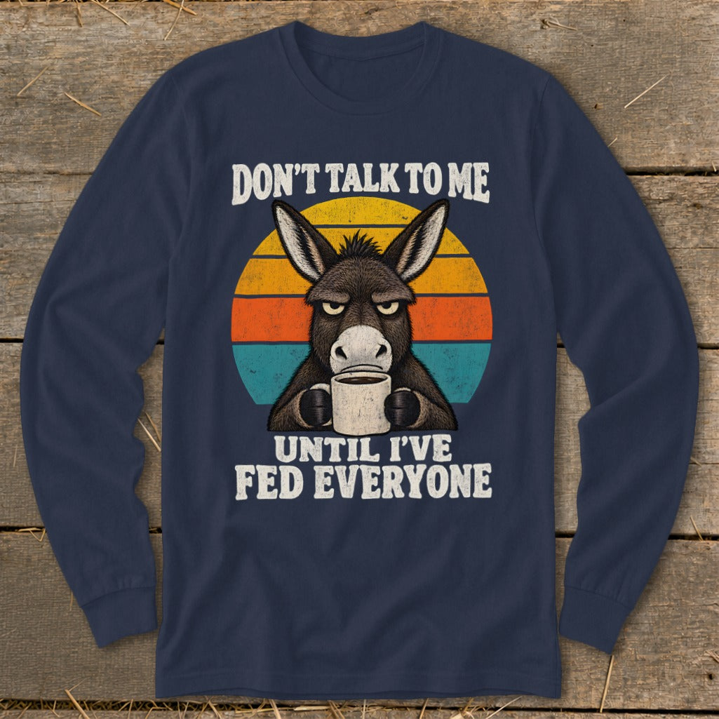 Dark blue long-sleeve t-shirt featuring a grumpy donkey holding a coffee mug against a retro sunset.
