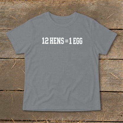A gray crewneck t-shirt with the white distressed text 12 HENS equals 1 EGG on the chest, laid flat on a rustic wooden background.