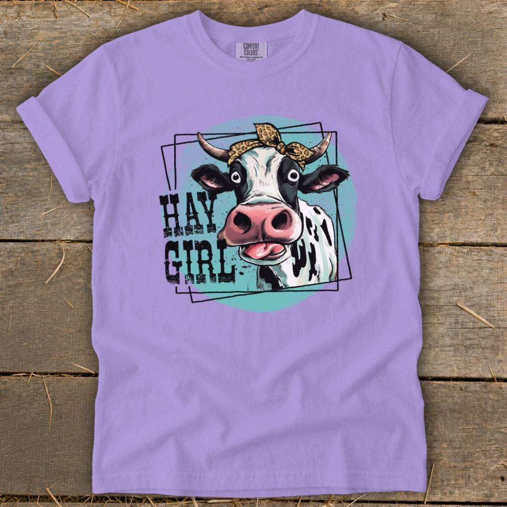 Lavender t-shirt with a graphic of a cow wearing a leopard print bandana and the text "HAY GIRL".