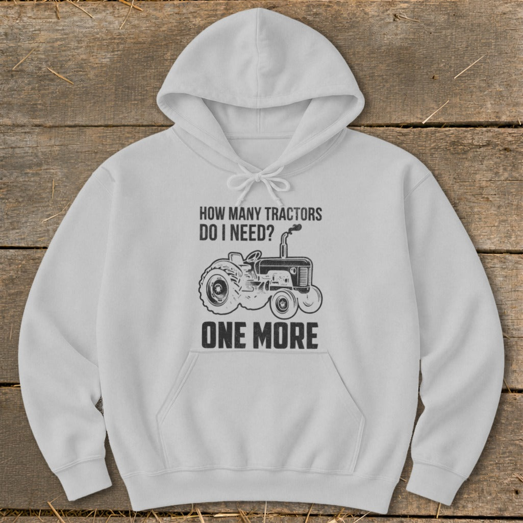White hoodie with text "HOW MANY TRACTORS DO I NEED? ONE MORE" and a tractor graphic.