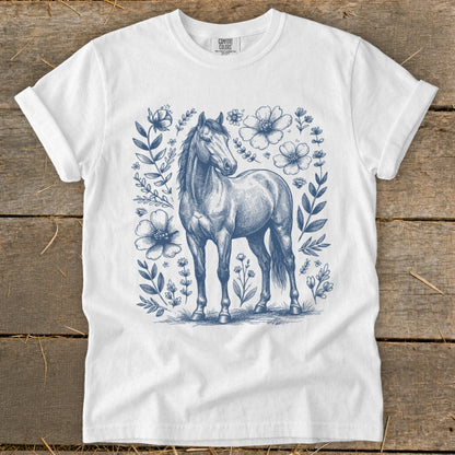 White t-shirt with blue sketch of a horse surrounded by flowers and leaves.