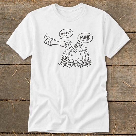 White t-shirt with cartoon hen saying "MINE" and hand reaching for eggs.