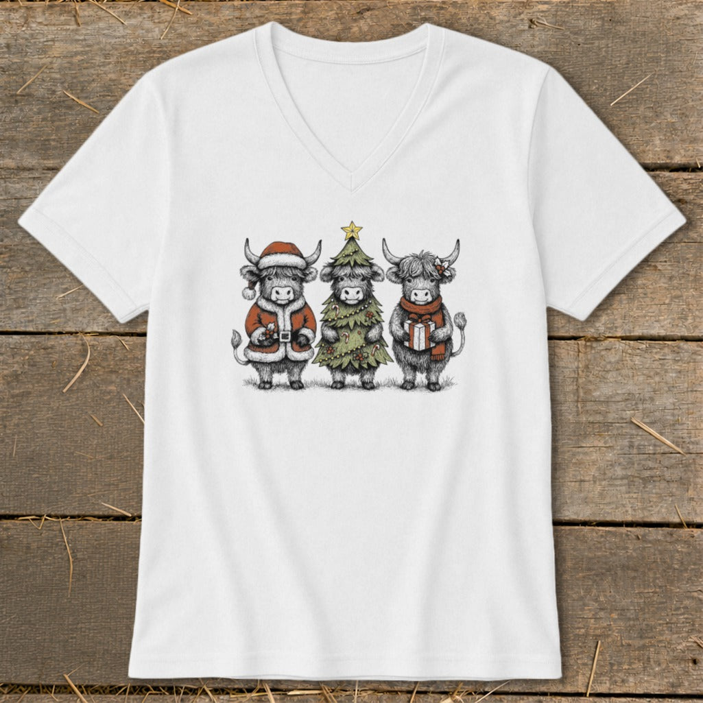 Three highland cows, dressed as Santa, a Christmas tree, and holding gifts, on a white t-shirt.