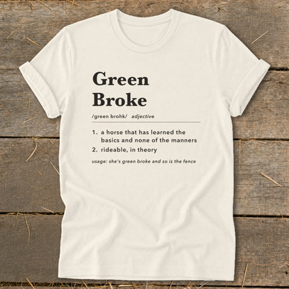 Off-white t-shirt with black dictionary-style text defining the term green broke centered on the chest, laid flat on a wooden surface.