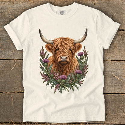 Highland cow portrait surrounded by thistles on a cream t-shirt.
