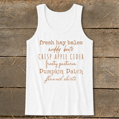 White tank top with fall-themed text: fresh hay bales, muddy boots, crisp apple cider, frosty pastures, pumpkin patch, flannel shirts.