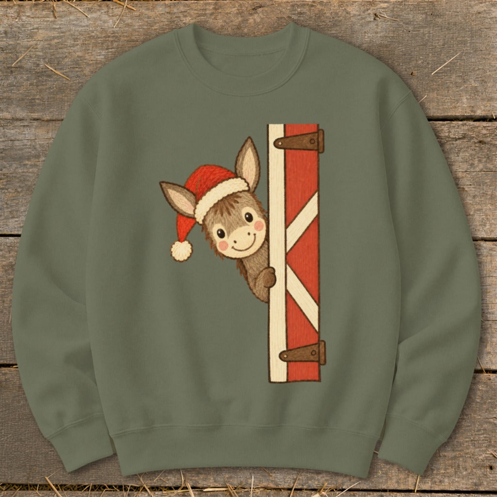 Donkey wearing Santa hat peeking around barn door graphic on a khaki sweatshirt.