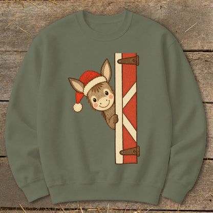 Donkey wearing Santa hat peeking around barn door graphic on a khaki sweatshirt.