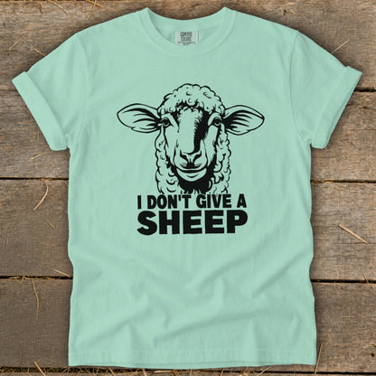 Light blue t-shirt with a black graphic of a sheep's head and text "I DON'T GIVE A SHEEP".