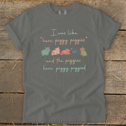 Grey t-shirt with "I was like 'here piggy piggies' and the piggies here piggy piggied" text and line of pigs.