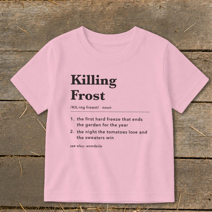 A light pink t-shirt with black dictionary-style text defining Killing Frost displayed flat on a wooden background.