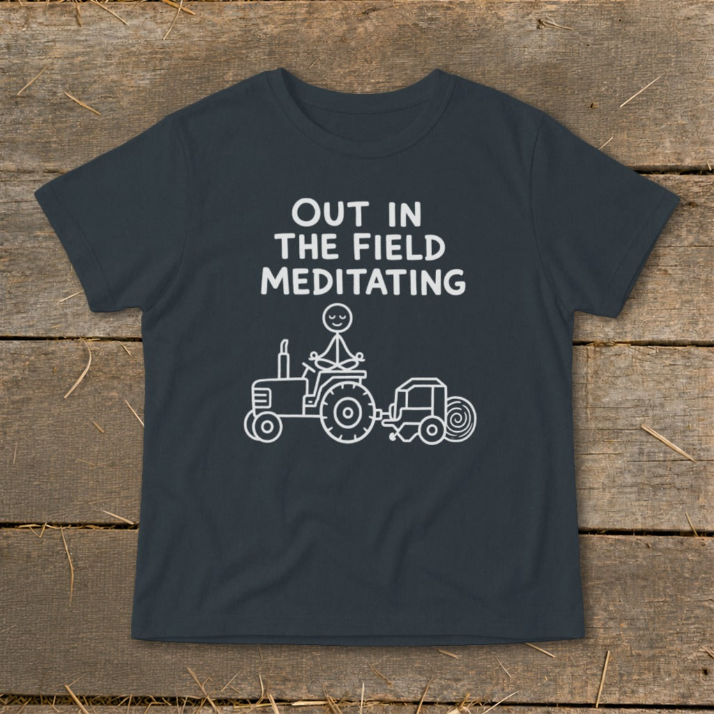 T-shirt with "OUT IN THE FIELD MEDITATING" text and stick figure meditating on a tractor.