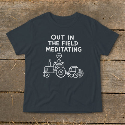 T-shirt with "OUT IN THE FIELD MEDITATING" text and stick figure meditating on a tractor.