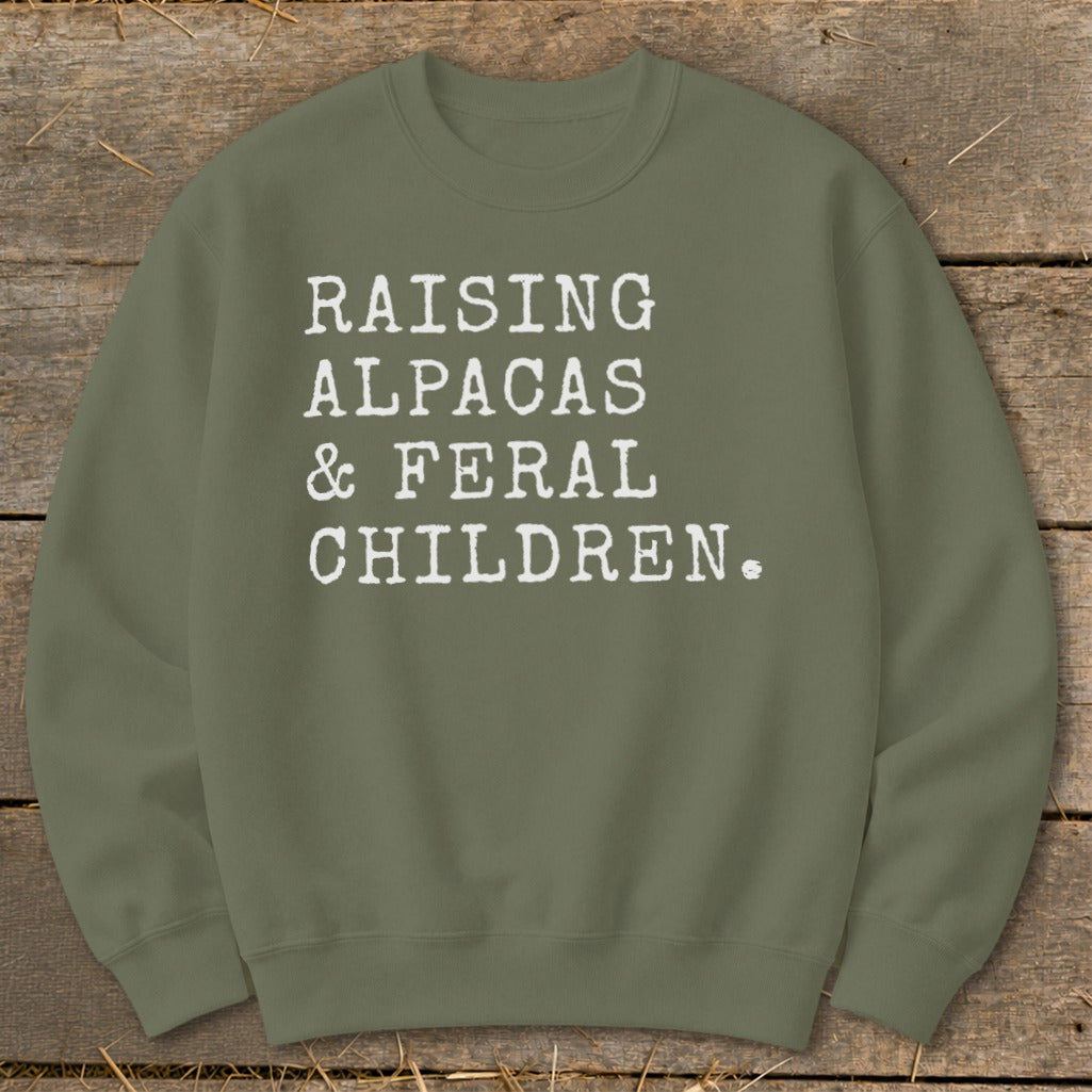 Olive green sweatshirt with white text: "Raising Alpacas & Feral Children."