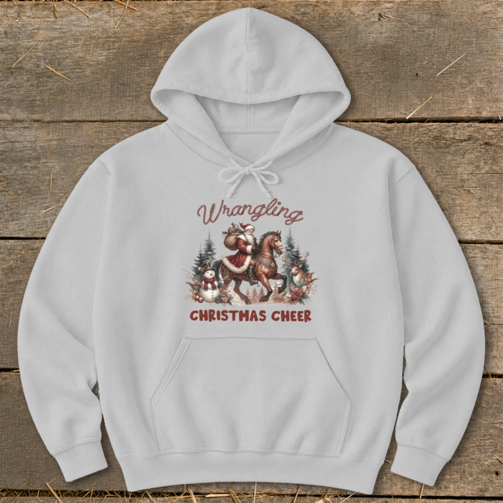 Light gray hoodie with a graphic of Santa on horseback surrounded by snowmen, reindeer, and trees. Text reads "Wrangling Christmas Cheer".