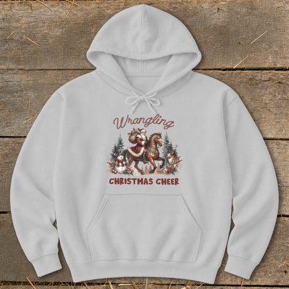 Light gray hoodie with a graphic of Santa on horseback surrounded by snowmen, reindeer, and trees. Text reads "Wrangling Christmas Cheer".