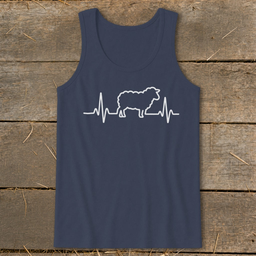Dark blue tank top featuring a white graphic of a sheep integrated into a heartbeat line, laid flat on a rustic wooden background.