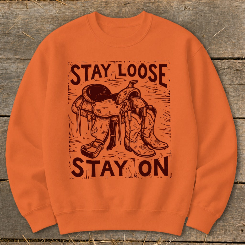 Orange sweatshirt with "STAY LOOSE" above a saddle and boots, "STAY ON" below.