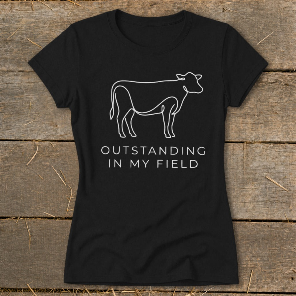 Black t-shirt with white line art of a cow and the text "OUTSTANDING IN MY FIELD".