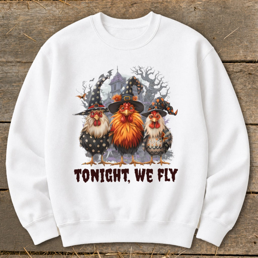 Three chickens in witch hats stand before a spooky haunted house, text reads "TONIGHT, WE FLY".