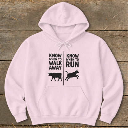 Light pink hoodie with black graphic: "Know When to Walk Away" with cow, "Know When to Run" with bull.