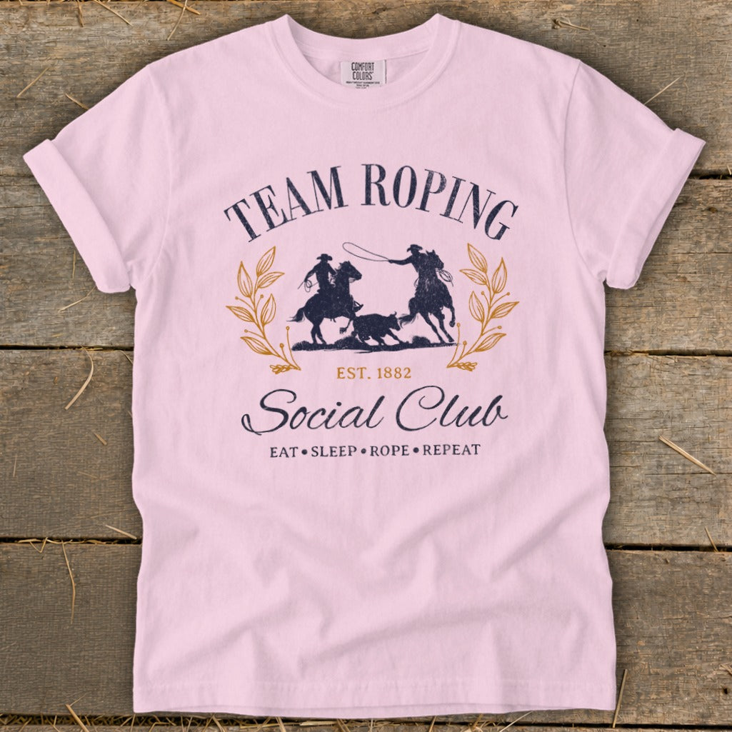 Pink t-shirt with "Team Roping Social Club" graphic and "Eat Sleep Rope Repeat" text.