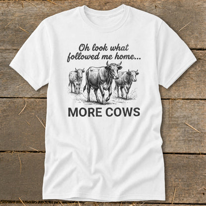 White t-shirt with sketch of three cows and text "Oh look what followed me home... MORE COWS".